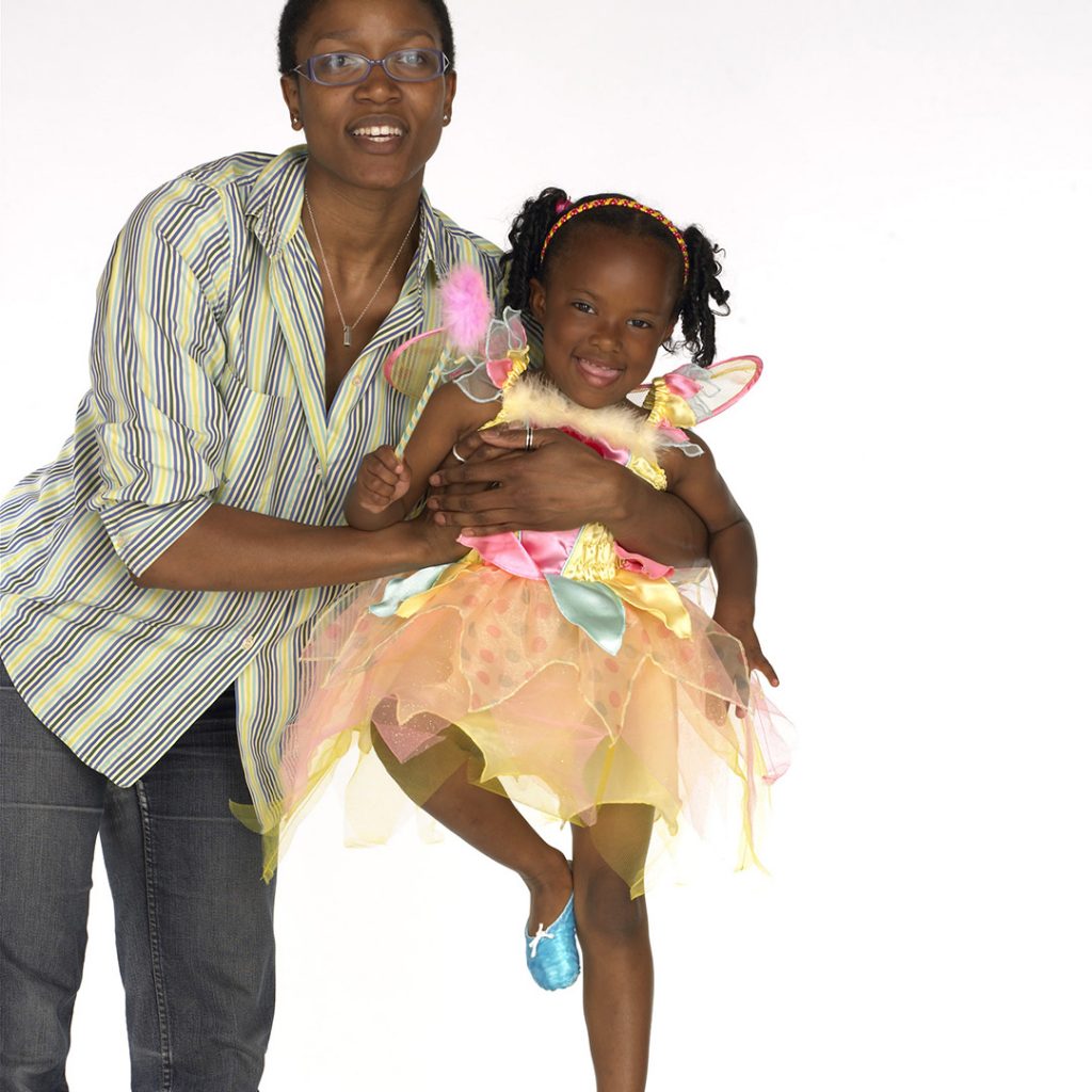 A woman holds up a little girl in a fairy costume.