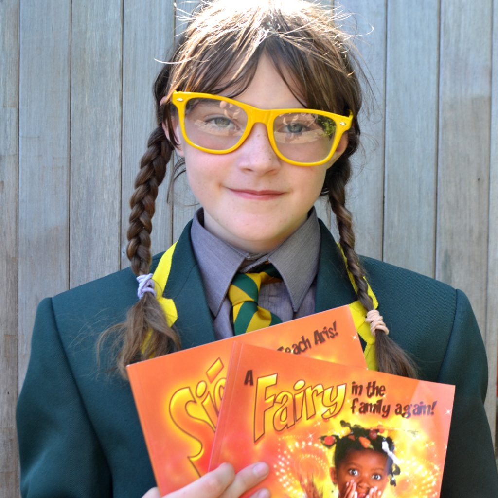 A girl in a school blazer with shirt and tie holds her dual language English and Irish book