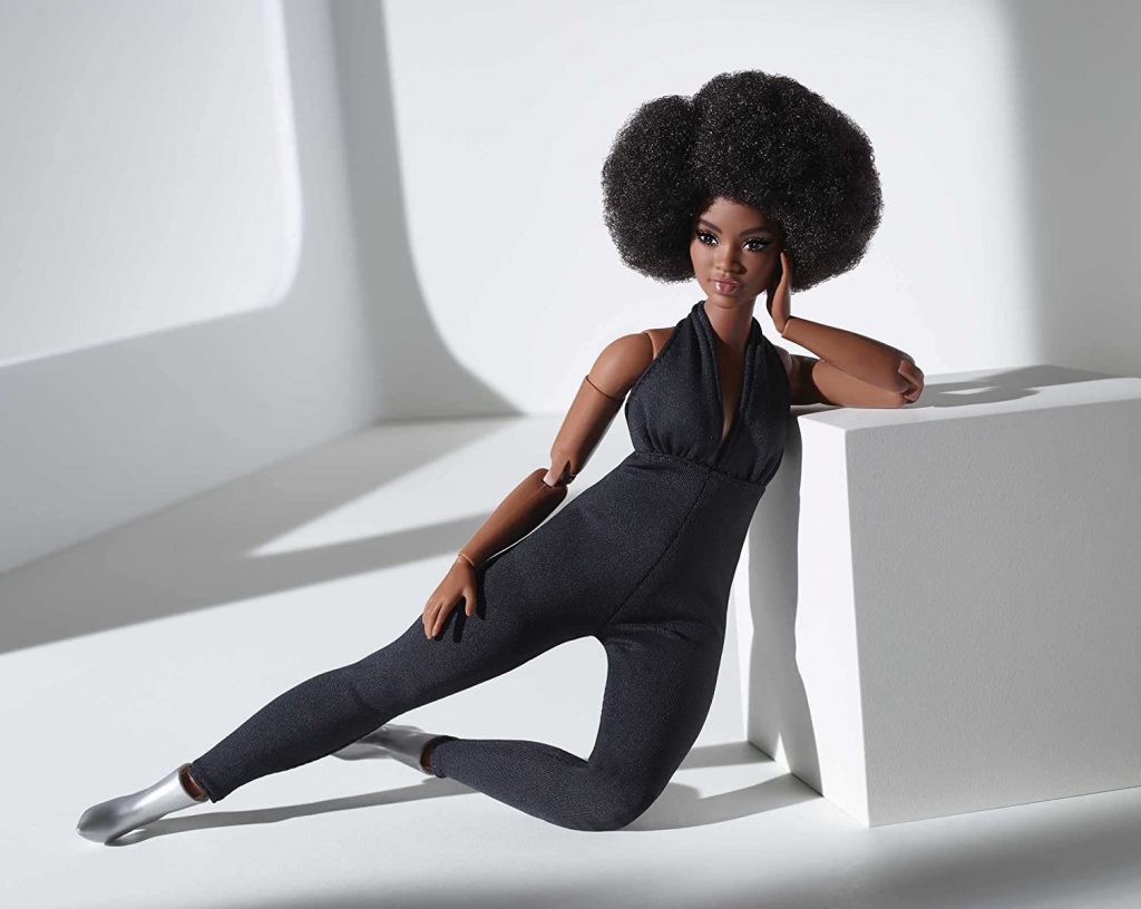 a curvy black doll poses in a jumpsuit