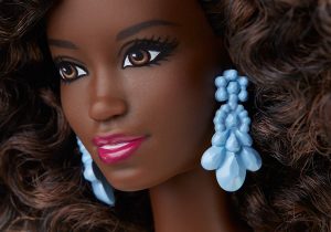 Face of an African-American barbie doll with curly hair and big earrings