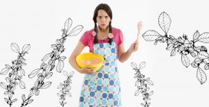 Angry girl in rose patterned apron waving a wooden spoon