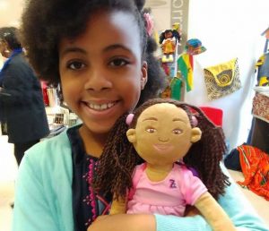 smiling little black girl holding a black plush doll